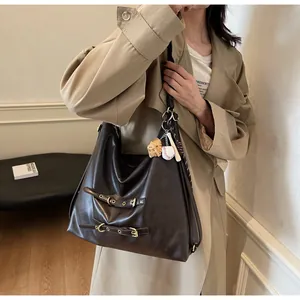Detail of dark brown vintage faux leather tote with baseball charm and decorative buckles