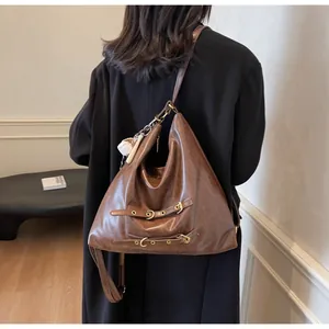 Detail of vintage brown oversized hobo bag with buckled straps and a mini baseball charm