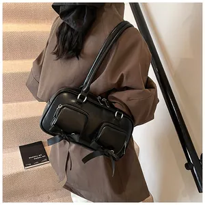 Detail of black leather shoulder bag featuring twin front zip pockets and ribbon bows