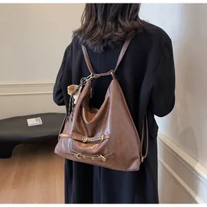 Detail of vintage brown leather backpack with metallic eyelets and straw pendant