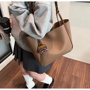 Close-up of brown litchi grain tote bag with leopard print charm and long shoulder strap