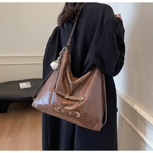 Brown vintage faux leather tote bag with metal buckle straps and baseball charm detail