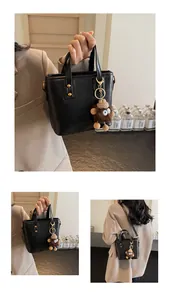Détail du sac seau en cuir noir avec rivets et breloque petit monstre en peluche