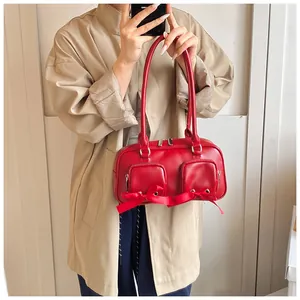 Detail of red PU leather shoulder bag featuring decorative silk bows and silver zippers