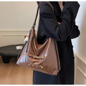 Detail of a large vintage brown hobo bag with gold buckles and a baseball charm