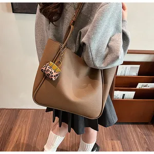 Macro detail of the brown leather tote bag texture and leopard print charm accessory