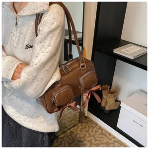 Deep brown shoulder bag with double zip pockets and silk bow detail shown on a model
