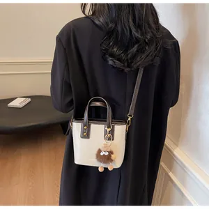 Détail d'un sac seau contrasté tendance avec breloque peluche rigolote en situation réelle