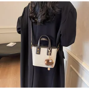 Vue arrière d'un mannequin portant le sac bandoulière crème et marron avec un charme en peluche