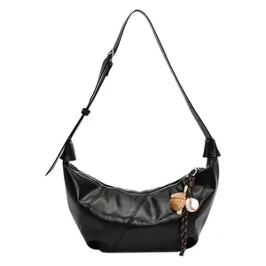 Bolso de hombro media luna negro brillante con costuras diagonales y colgante de béisbol