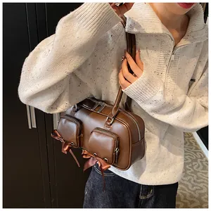 Detail of brown vintage shoulder bag with front zipper pockets and satin ribbon bows