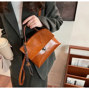 Detailansicht der braunen Lederhandtasche mit silbernem Drehverschluss und Flechtanhänger