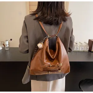 Detail of vintage brown leather tote bag featuring metal buckles and baseball charm