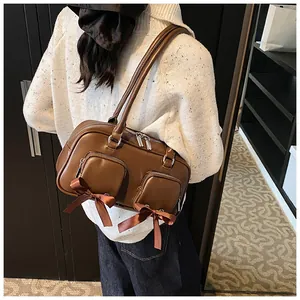Detail view of brown shoulder bag with bow accents and twin zip pockets in high quality PU leather