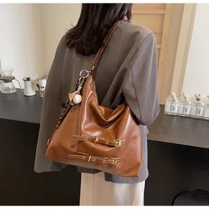 Retro brown leather tote bag with dual metal buckles and decorative baseball charm