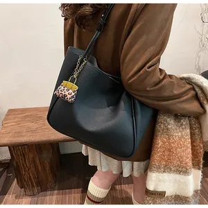 Detail of black pebbled leather tote bag featuring a stylish leopard print charm accessory