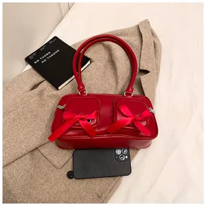 Detail of red glossy PU shoulder bag with silk bows and dual zipper front pockets