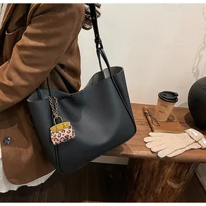 Close-up of black lychee leather tote bag with stylish leopard print mini charm