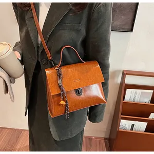Braune Vintage-Handtasche mit Metallschnalle und Glockenanhänger zum grünen Cordblazer