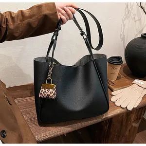Macro shot of black pebbled leather tote bag with stylish leopard print charm accessory