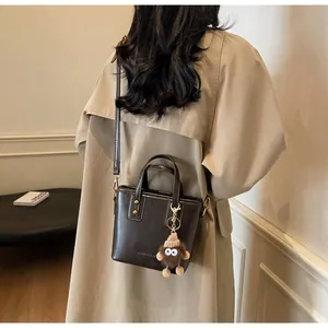 Détail du mini sac cabas marron foncé avec texture cuir et breloque en peluche