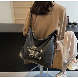 Detailed back view of model wearing a large black leather tote bag with buckle straps