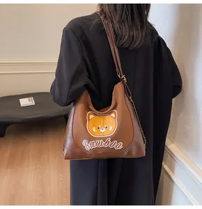 Détail de la broderie ours et du texte Bambaa sur un sac fourre-tout en cuir marron