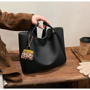 Close-up of black tote bag with lychee grain texture and stylish leopard print charm