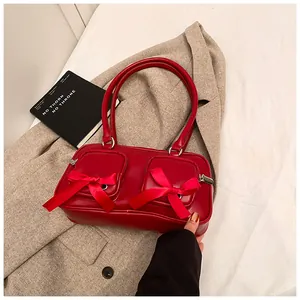 Detail of red faux leather shoulder bag with decorative bows and zippered front pockets
