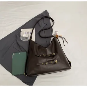 Detail of dark brown faux leather tote bag with vintage buckles and baseball charm