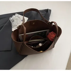 Interior view of brown tote bag showing zipper compartment with iPad and daily items