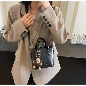 Détail du sac seau en cuir noir avec clous dorés et breloque en peluche marron