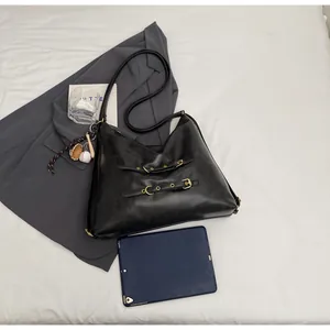 Detail of black leather hobo bag with gold buckles and baseball charm for daily commute
