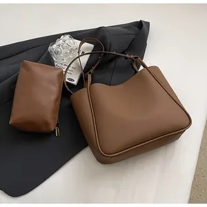 Detail of caramel brown pebbled leather tote bag set on black blazer with lifestyle props
