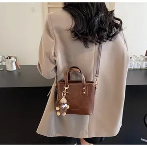 Détail du mini cabas marron foncé avec charm monstre en peluche et bandoulière en cuir
