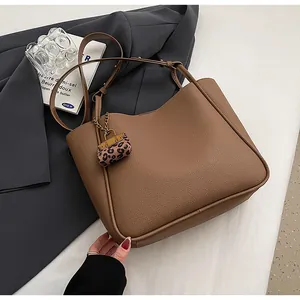 Detail of brown leather tote bag with a trendy leopard print pouch and adjustable strap