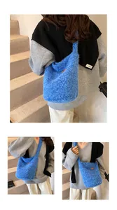 Detailed close-up of blue soft plush shoulder bag with brown leather label on the front