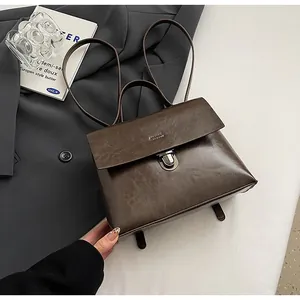 Detail eines dunkelbraunen Lederrucksacks mit Metalldrehverschluss und Vintage-Klappe
