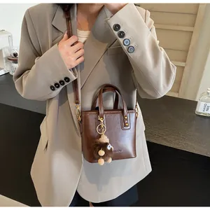 Détail du sac seau vintage en cuir marron avec charme en peluche et boucles dorées