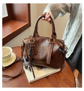 Detail of vintage coffee leather Boston bag with chocolate charm and textured surface