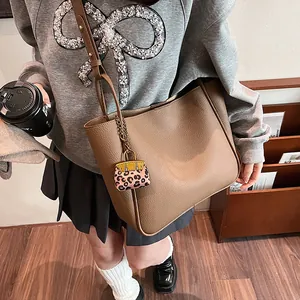 Deep brown pebble leather tote bag with leopard print charm in a stylish street style view