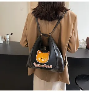 Détail du sac à bandoulière en cuir PU noir avec broderie ours jaune et lettrage d'art