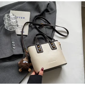 Détail du sac seau blanc cassé avec poignées brunes et pendentif en peluche