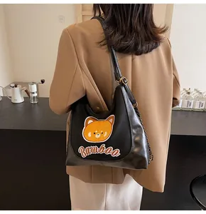 Détail du sac à bandoulière noir avec broderie mignonne et bandoulière en chaîne dorée