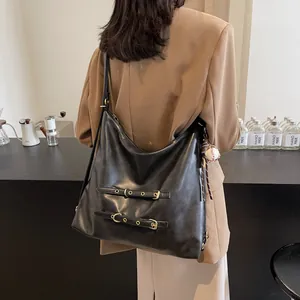 Retro black faux leather hobo bag with gold buckles worn by a model in a cozy cafe
