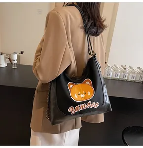 Détail du sac cabas noir avec broderie ours et accents de bandoulière en chaîne métal
