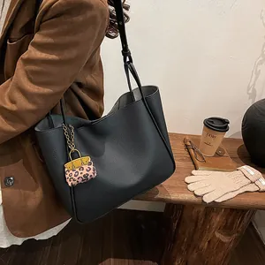 Black pebble leather tote bag with leopard print charm and shoulder strap for women