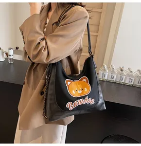 Détail de la broderie ours et chaîne métallique sur le sac fourre-tout noir décontracté