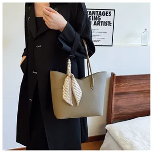 Détail d'un cabas en cuir grainé vert olive avec une poignée ornée d'un foulard en soie