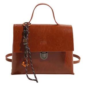Minimalistische dunkelbraune Handtasche mit Lederstruktur und elegantem Glockenanhänger